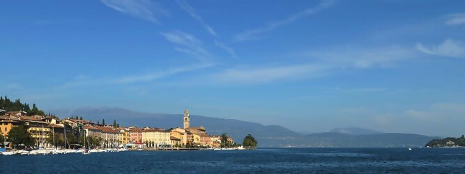 Trip Nordmazedonien beliebte Urlaubsziele am Gardasee -  Mit einer Fläche von 370 km² ist der Gardasee der größte See Italiens. Es liegt am Fuße der Alpen und erstreckt sich über drei Staaten: Lombardei, Venetien und Trentino. Die maximale Tiefe des Sees beträgt 346 m, er hat eine längliche Form und sein nördliches Ende ist sehr schmal. Dort ist der See von den Bergen der Gruppo di Baldo umgeben. Du trittst aus deinem gemütlichen Hotelzimmer und es begrüßt dich die warme italienische Sonne. Du blickst auf den atemberaubenden Gardasee, der in zahlreichen Blautönen schimmert - von tiefem Dunkelblau bis zu funkelndem Türkis. Majestätische Berge umgeben dich, während die Brise sanft deine Haut streichelt und der Duft von blühenden Zitronenbäumen deine Nase kitzelt. Du schlenderst die malerischen, engen Gassen entlang, vorbei an farbenfrohen, blumengeschmückten Häusern. Vereinzelt unterbricht das fröhliche Lachen der Einheimischen die friedvolle Stille. Du fühlst dich wie in einem Traum, der nicht enden will. Jeder Schritt führt dich zu neuen Entdeckungen und Abenteuern. Du probierst die köstliche italienische Küche mit ihren frischen Zutaten und verführerischen Aromen. Die Sonne geht langsam unter und taucht den Himmel in ein leuchtendes Orange-rot - ein spektakulärer Anblick.